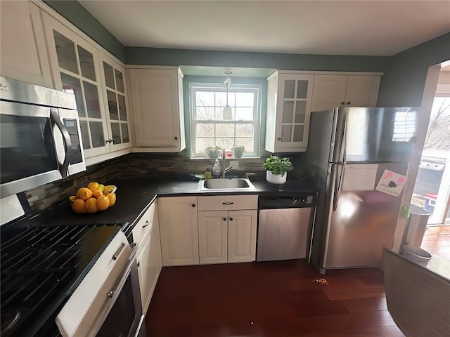 kitchen with stainless steel appliances, glass insert cabinets, a sink, and white cabinetry