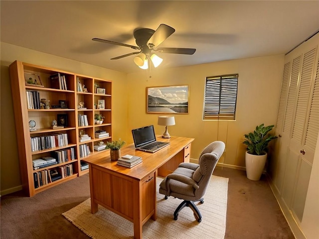 carpeted office space with baseboards and a ceiling fan