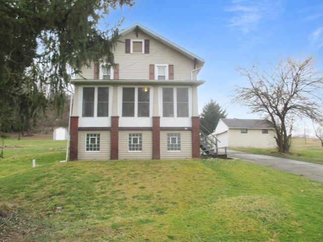 view of front of house featuring driveway, a garage, a sunroom, stairway, and a front lawn