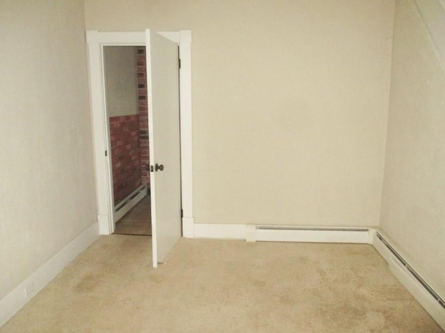 carpeted spare room with a baseboard heating unit