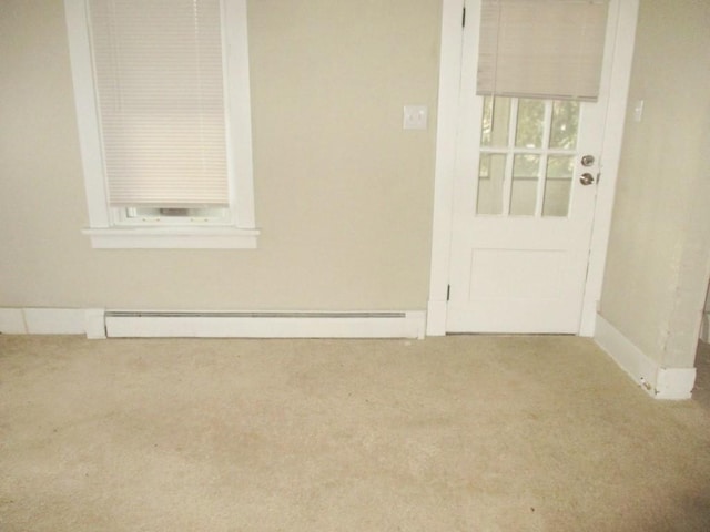 carpeted spare room featuring a baseboard heating unit and baseboards