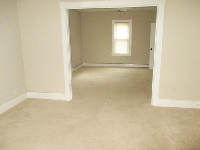 empty room with a baseboard heating unit, carpet flooring, and baseboards