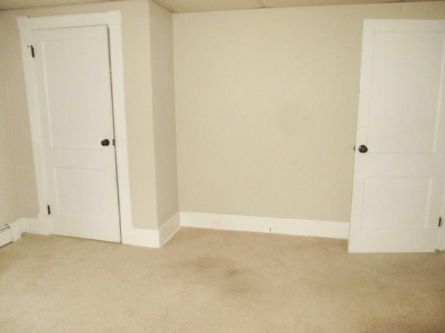 empty room featuring baseboards and light colored carpet