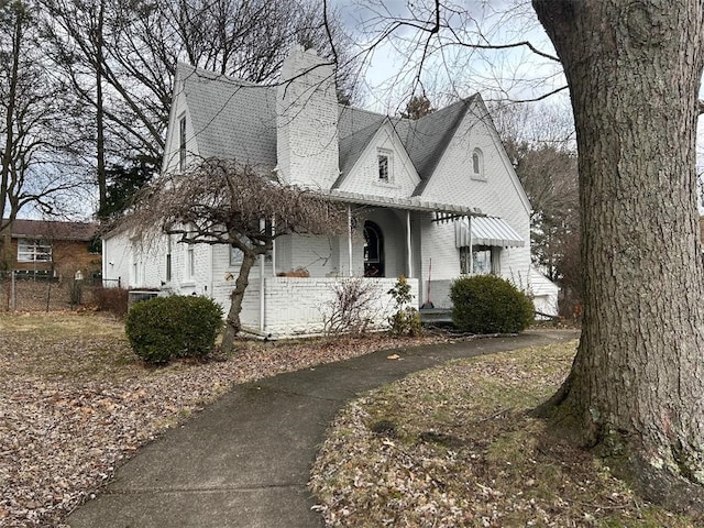 view of front of home featuring a shingled roof, brick siding, and fence