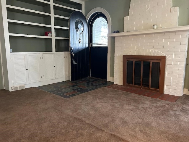 unfurnished living room featuring carpet floors, visible vents, and a fireplace