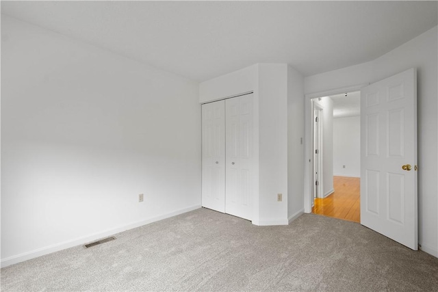 unfurnished bedroom with a closet, carpet, visible vents, and baseboards