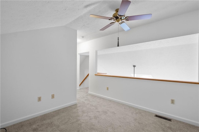 unfurnished room featuring a textured ceiling, ceiling fan, carpet flooring, visible vents, and baseboards