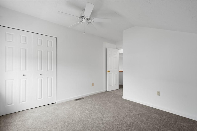 unfurnished bedroom with baseboards, visible vents, vaulted ceiling, carpet floors, and a closet