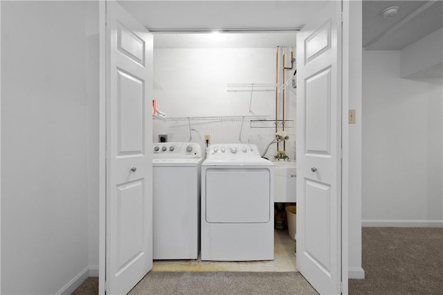 laundry room with laundry area, light colored carpet, baseboards, and washing machine and clothes dryer