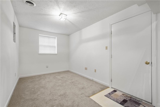 carpeted spare room featuring baseboards, visible vents, and a textured ceiling