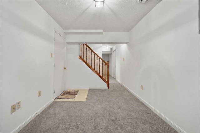 carpeted spare room with a textured ceiling, baseboards, and stairs