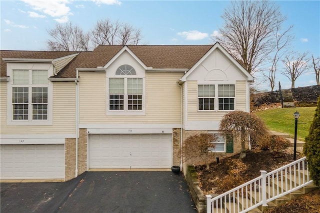 view of front of house featuring driveway, a garage, stairs, and brick siding