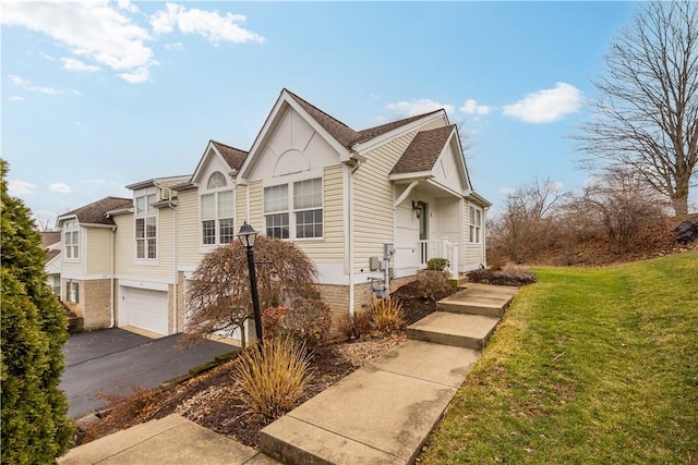 view of front of property with an attached garage, driveway, roof with shingles, and a front yard