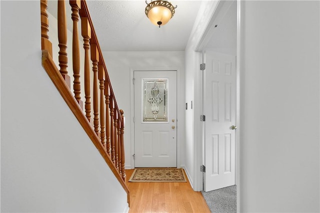 doorway to outside with stairs, light wood finished floors, and baseboards