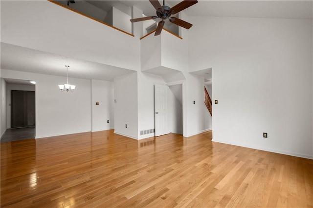 unfurnished living room with light wood-type flooring, visible vents, stairway, and ceiling fan with notable chandelier