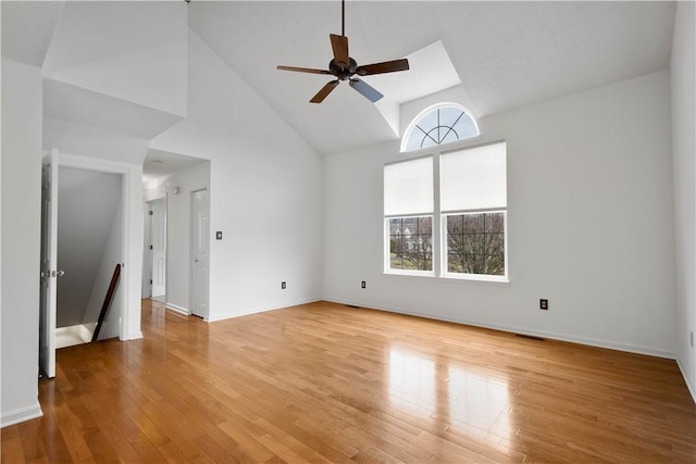 spare room with high vaulted ceiling, baseboards, and light wood finished floors