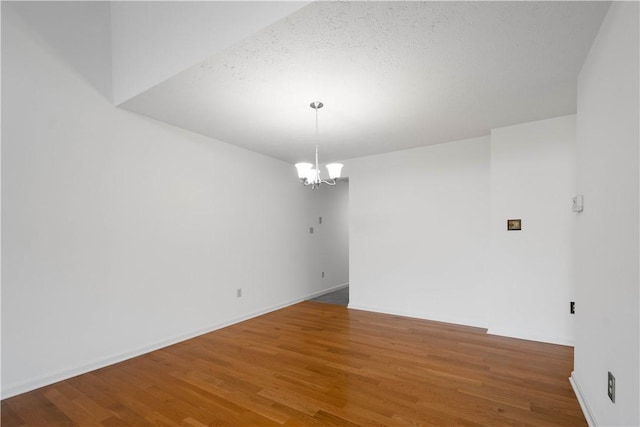 spare room with a chandelier and wood finished floors