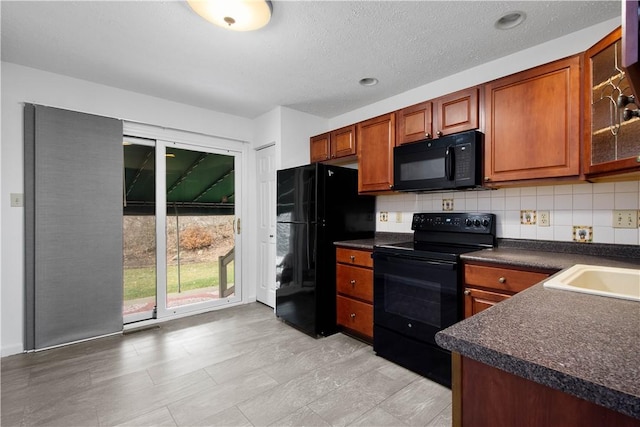 kitchen featuring dark countertops, black appliances, tasteful backsplash, and glass insert cabinets