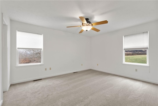 unfurnished room featuring carpet floors, visible vents, baseboards, and a wealth of natural light