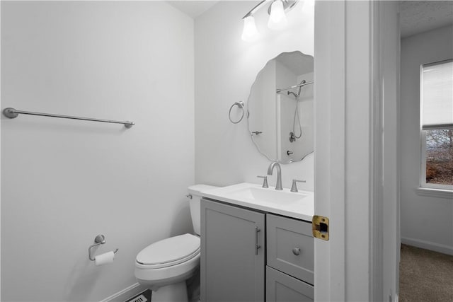 bathroom featuring toilet, baseboards, walk in shower, and vanity