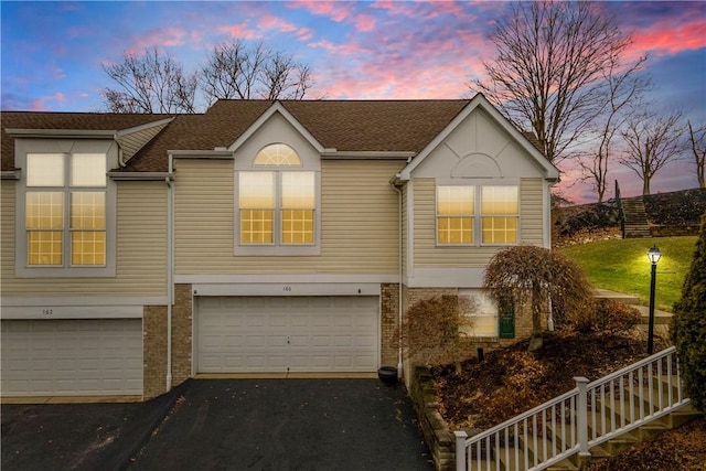 view of front of home with a garage, driveway, brick siding, and a shingled roof