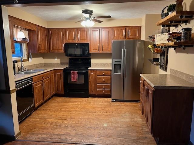 kitchen featuring black appliances, a ceiling fan, a sink, open shelves, and light wood-style floors