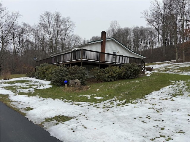 snow covered property featuring a chimney and a wooden deck