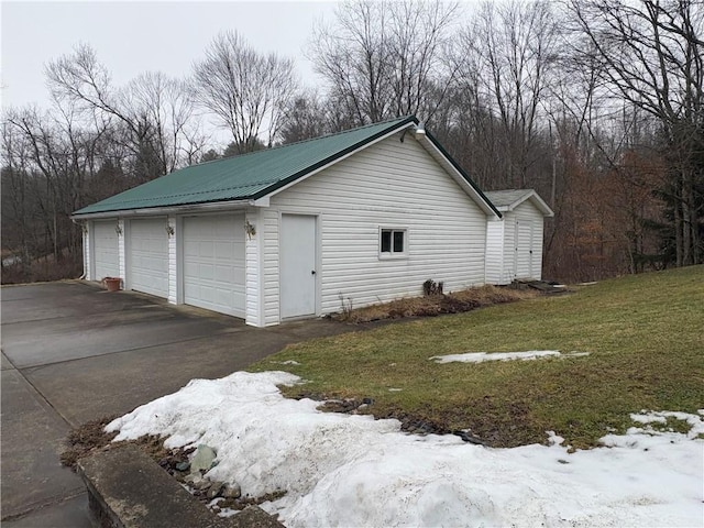 view of side of home featuring a garage, metal roof, an outdoor structure, and a lawn