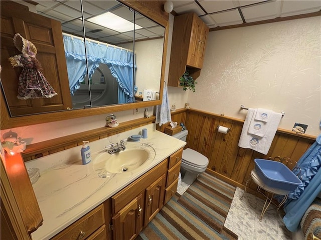 bathroom with a wainscoted wall, a paneled ceiling, toilet, wood walls, and vanity