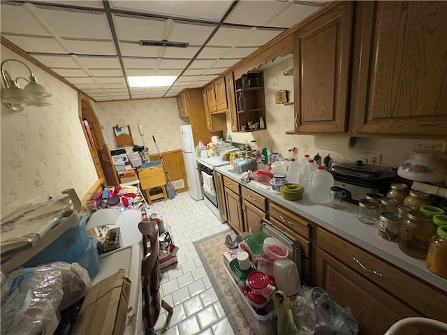 kitchen featuring wallpapered walls, electric range, brown cabinets, freestanding refrigerator, and light countertops