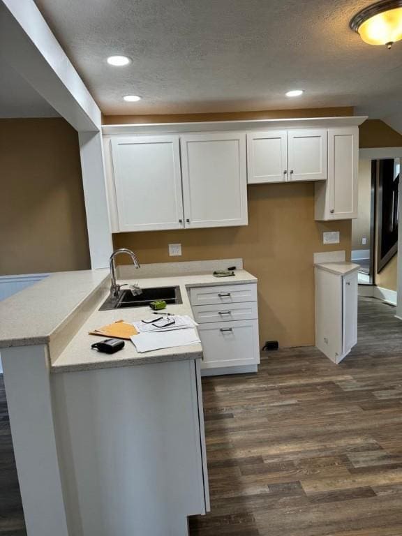 kitchen featuring a peninsula, white cabinets, and a sink