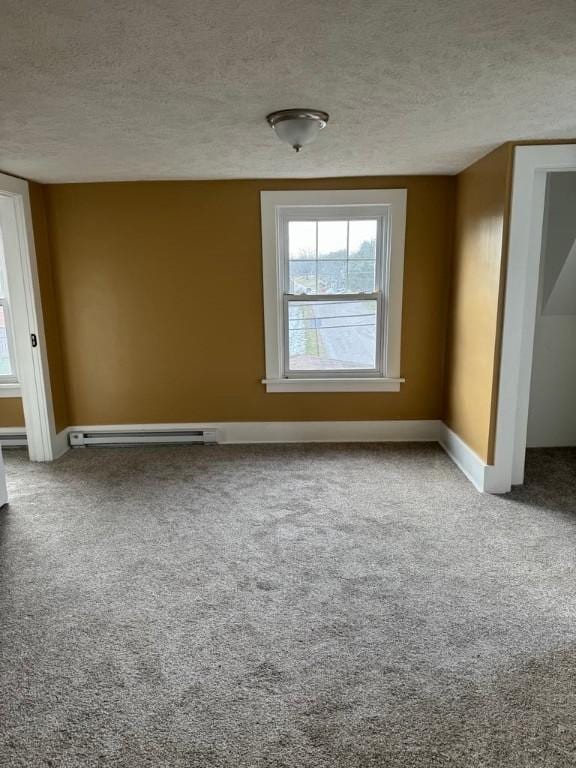 spare room with carpet, baseboards, baseboard heating, and a textured ceiling