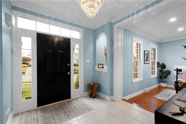 entrance foyer featuring light tile patterned floors, baseboards, an inviting chandelier, crown molding, and a healthy amount of sunlight