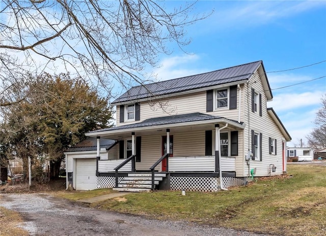 view of front facade with covered porch, metal roof, a front lawn, and a garage