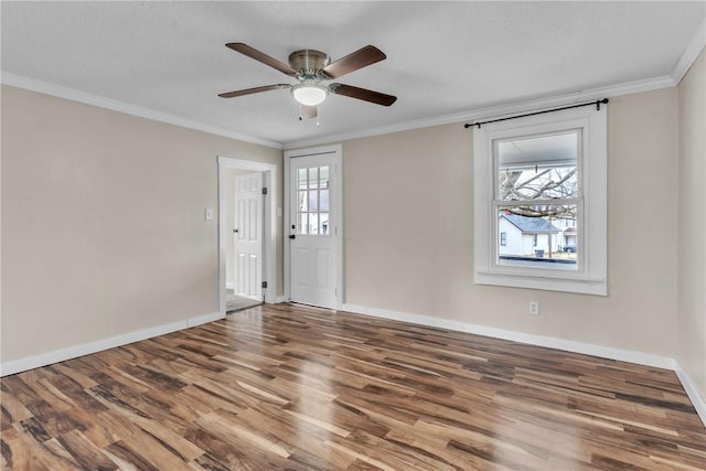 spare room featuring ornamental molding, a ceiling fan, baseboards, and wood finished floors