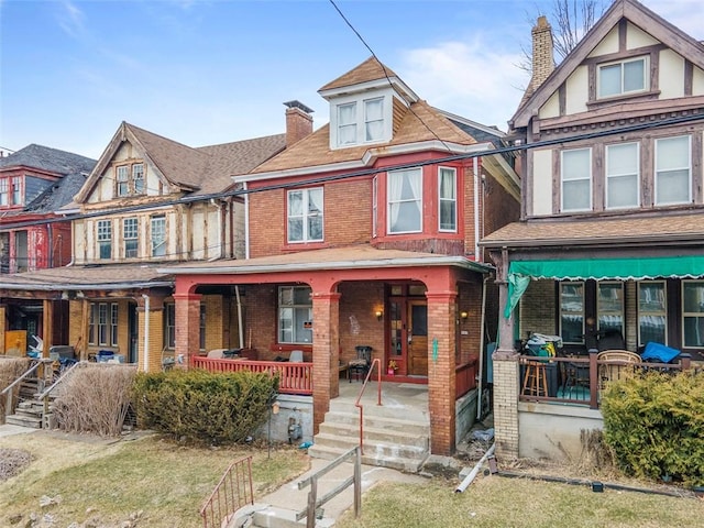 view of front facade featuring a porch, a chimney, and brick siding