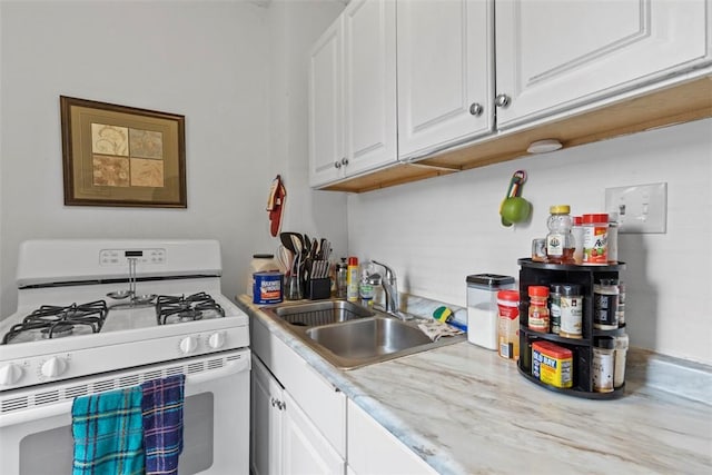 kitchen with light countertops, white gas range oven, a sink, and white cabinetry