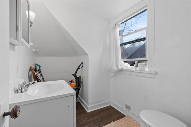 half bath featuring toilet, baseboards, wood finished floors, and vanity