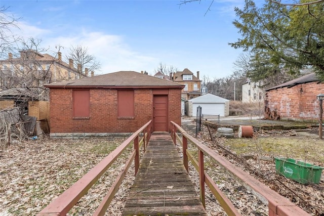 back of house with a garage, brick siding, and an outdoor structure