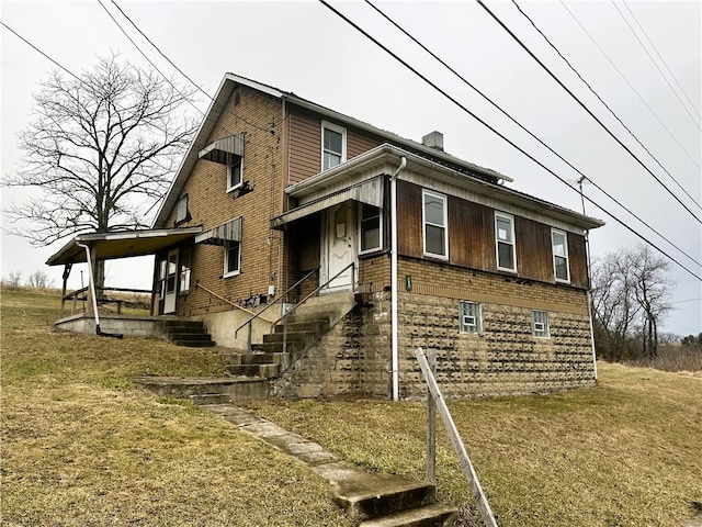 view of front of house with a front yard, brick siding, and a chimney