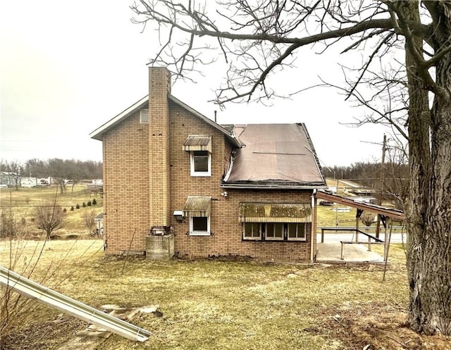 back of house featuring brick siding and a chimney