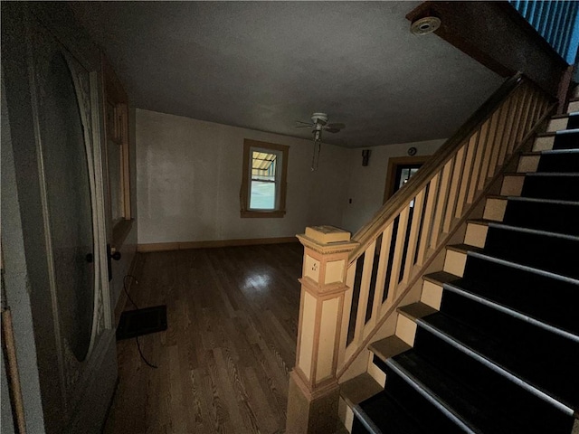 stairway with ceiling fan, a textured ceiling, baseboards, and wood finished floors