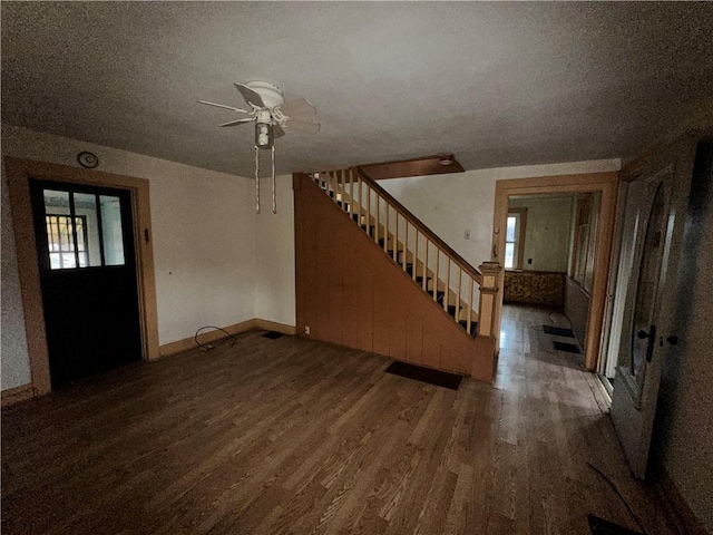 unfurnished living room with stairs, a textured ceiling, and wood finished floors