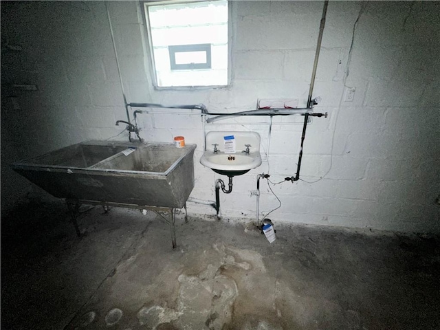 below grade area featuring concrete block wall and a sink