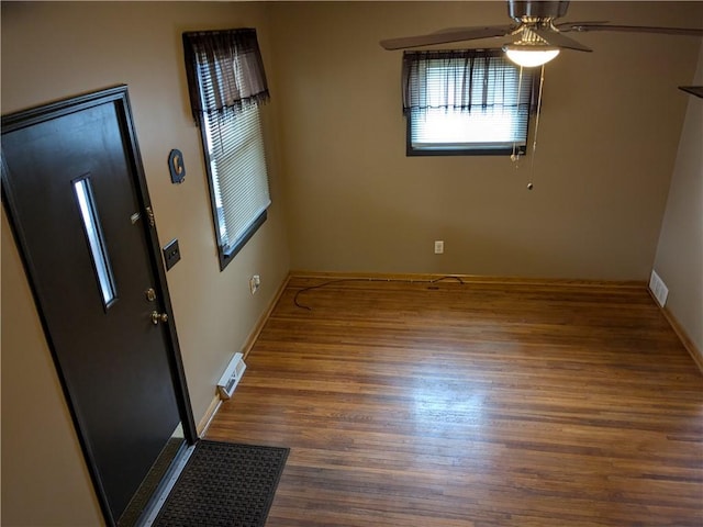 foyer with visible vents, wood finished floors, a ceiling fan, and baseboards