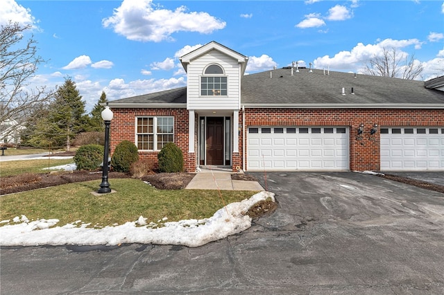 view of front of property with a garage, brick siding, a shingled roof, driveway, and a front yard