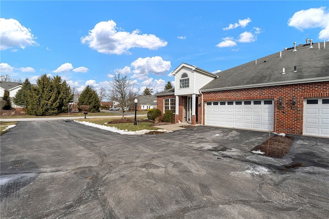 view of front of property with aphalt driveway, brick siding, a shingled roof, and an attached garage