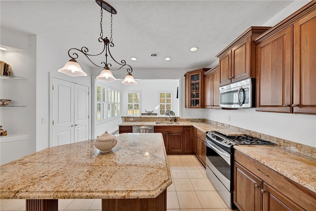 kitchen featuring brown cabinets, stainless steel appliances, a sink, and a center island