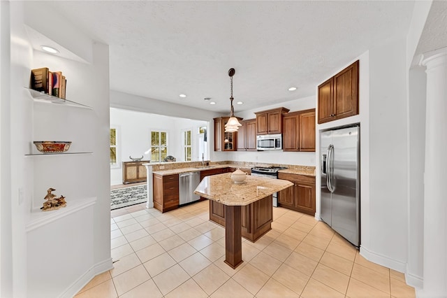 kitchen with stainless steel appliances, a peninsula, a sink, a center island, and light stone countertops