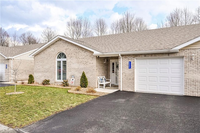 ranch-style house with aphalt driveway, roof with shingles, brick siding, an attached garage, and a front lawn